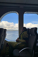 Ein Student sitzt auf einer Fähre am Fenster und schaut auf das Wasser.
