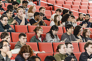 Studierende sitzen auf den roten Stühlen im Audimax der TU Braunschweig.