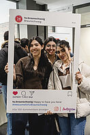 Drei Studentinnen posieren mit einem Instagram-Fotorahmen beim Welcome Week-Kick off für ein Foto.