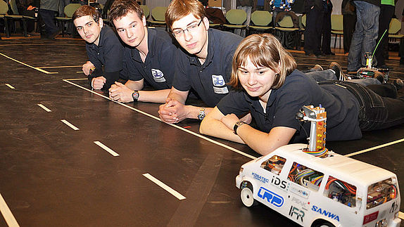 Studierende betrachten ein autonomes Modellfahrzeug beim Carolo Cup