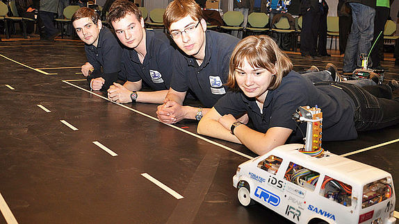 Studierende betrachten ein autonomes Modellfahrzeug beim Carolo Cup