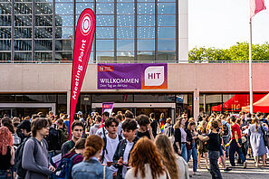 Eine Menschenmenge steht auf dem Universitätsplatz. Im Hintergrund ist das Audimax zu sehen, dort hängt ein Banner auf dem steht Willkommen - Dein Tag an der Uni.