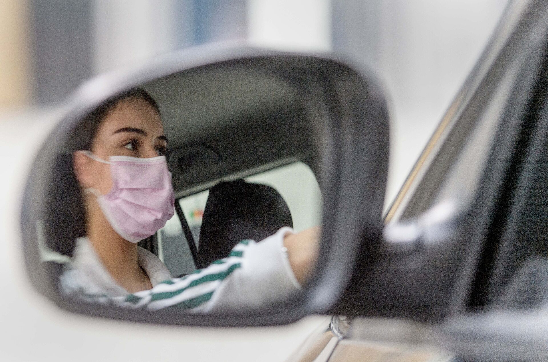 Frau mit Corona-Schutzmaske im Auto