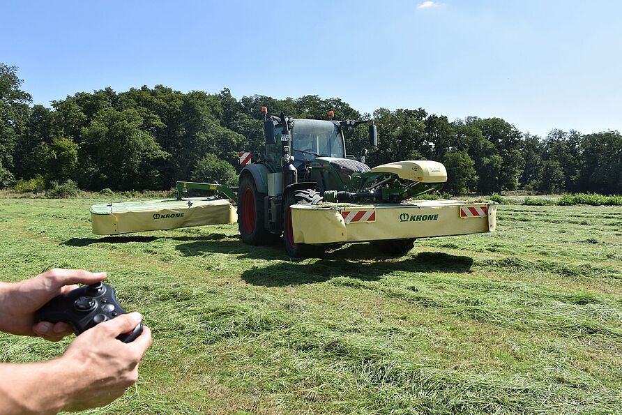 Das Symbolbild zeigt einen Traktor mit Front- und Heckmähwerk sowie einen Controller. An verschiedenen Möglichkeiten und Rahmenbedingungen der externen Steuerung als Schritt zur Automatisierung landwirtschaftlicher Maschinen und Prozesse wird im Projekt GESAL gearbeitet.