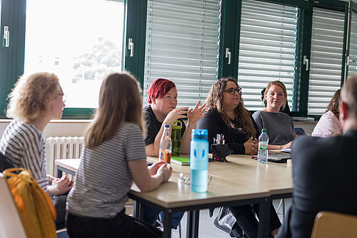 Studierende diskutieren in einem Seminarraum