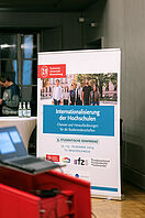 A roll-up with the inscription ‘Internationalisation of universities’ and details of the conference stands behind a speaker's desk in the auditorium of the Haus der Wissenschaft.