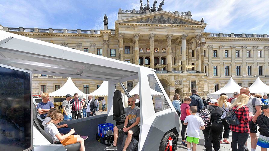BesucherInnen im Versuchsfahrzeug RAION auf dem Schlossplatz während des "Public Day" am 3. Juni 2023 in Braunschweig.