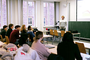 Participants sit in a seminar room and listen to a speaker.