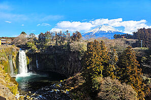 Blick auf den Berg Fuji mit einem Wasserfall im Vordergrund.
