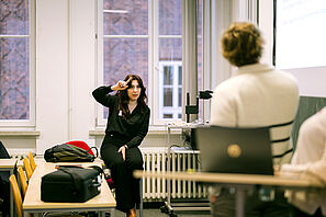A workshop participant raises her hand. Other workshop participants can be seen in the foreground.