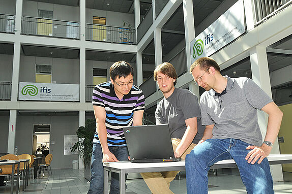 Drei Studierende vor einem Laptop im Institut