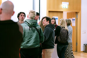Conference participants stand at a bar table and chat.