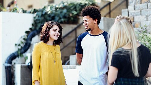 Three students exchanging ideas outside