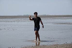 A participant of the summer school laughs into the camera during the tidal flat hike.