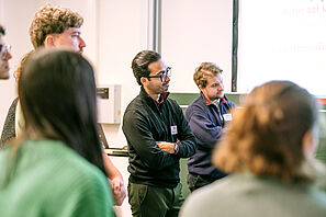 Conference participants stand in a circle during a workshop and exchange ideas.