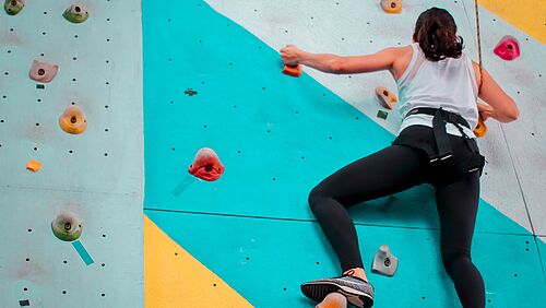 A woman climbs on a climbing wall