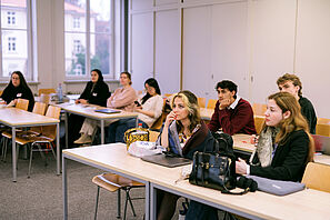Participants sit in a seminar room and listen attentively.