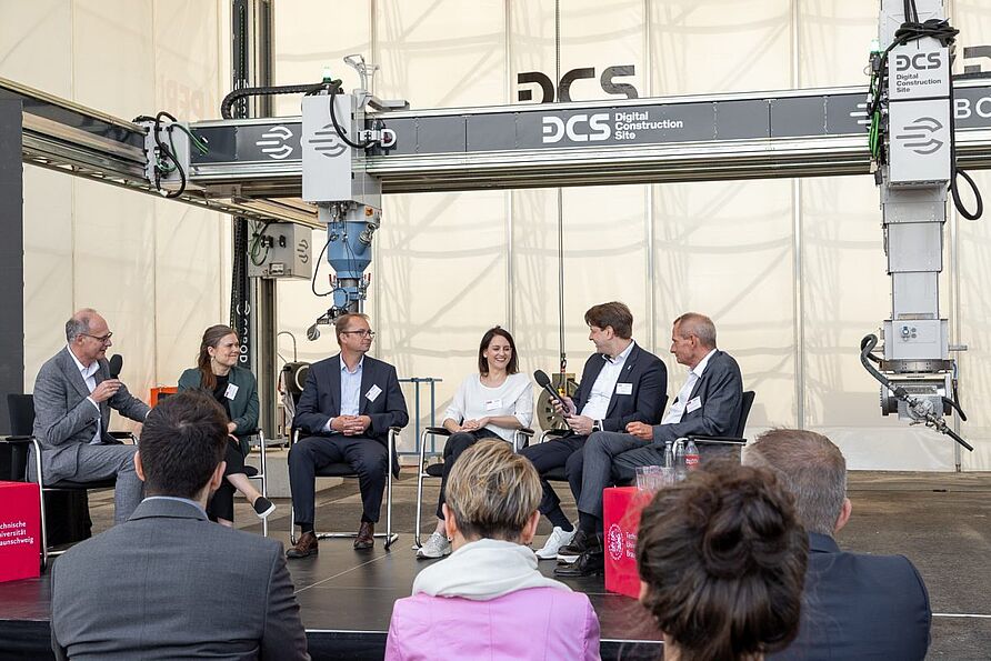 Podiumsdiskussion unter der Moderation von Professor Harald Kloft mit Helga Kühnhenrich, Referatsleiterin für Forschung und Innovation im Bauwesen beim Bundesinstitut für Bau-, Stadt- und Raumforschung (BBSR), Thorsten Leusmann, Oberingenieur am iBMB/Fachgebiet Baustoffe der TU Braunschweig, Kathrin Dörfler, Professorin für Digital Fabrication an der TU München und Co-Sprecherin des DFG-Sonderforschungsbereiches TRR 277 Additive Manufacturing in Construction, Maik Zutz, Technischer Bereichsleiter Direktion Nord bei der Ed. Züblin AG und Henrik Lund-Nielsen, Gründer und geschäftsführender Gesellschafter von COBOD International A/S.
