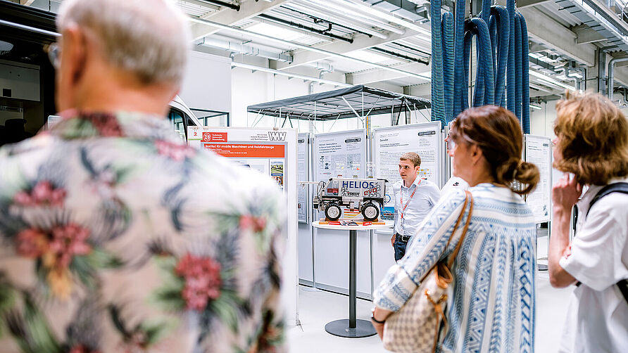 CampusXperience im NFF-Technikum: Wissenschaftlicher Mitarbeiter erläutert autonomen Feldroboter des IMN einer Besuchergruppe.