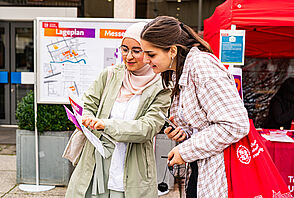 Zwei Studieninteressierte schauen gemeinsam in das HIT-Programmheft