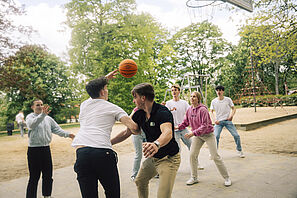Students are playing basketball in the theatre park.