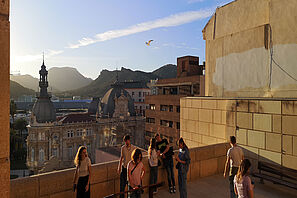 Ein sonniges historisches Stadtviertel mit Bergen im Hintergrund.