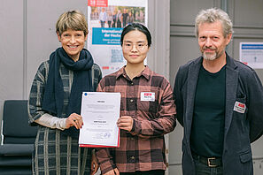 TU President Angela Ittel presents DAAD prizewinner Wei Zhao with a certificate. Prof Andreas Dietzel stands next to her.