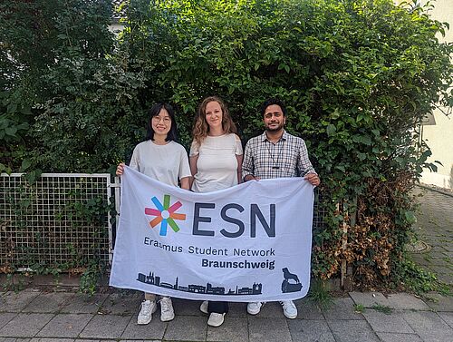 Drei Studierende mit einem Banner vom Erasmus Student Network