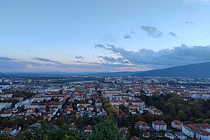 Ein Blick über die Stadt Maribor am Fuße eines großen Berges, der im Hintergrund zu sehen ist.