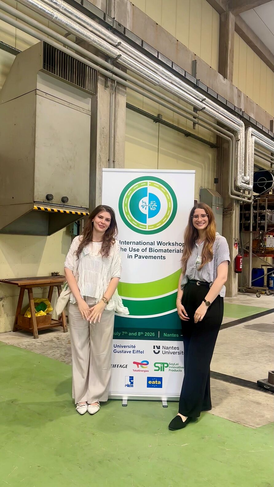 Tess Sigwarth und Marcela Krau vor einem Konferenzbanner
