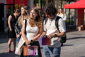 Schüler und Schülerinnen stehen auf dem Universitätsplatz und studieren das HIT Programmheft.