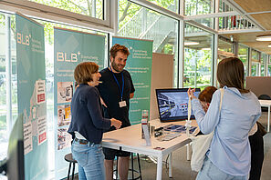 Mitarbeitende der BatteryLab Factory der TU Braunschweig unterhalten sich mit SchülerInnen an einem Stand.