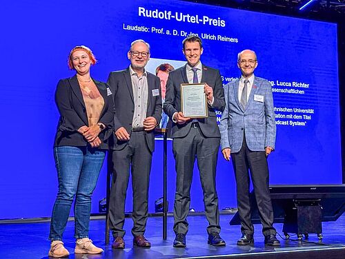 Dr. Lucca Richter umgeben von Sonja Langhans (2. Vorsitzende der FKTG), Prof. Dr.-Ing. Rainer Schäfer (Vorsitzender) und Prof. a. D. Dr.-Ing. Ulrich Reimers. 
