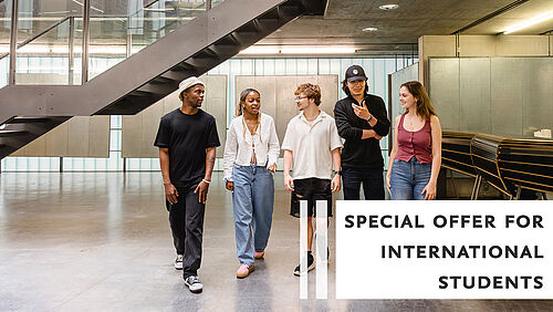 Eine Gruppe von Studierenden geht nebeneinander durch den Architekturpavillon der TU Braunschweig und unterhält sich dabei. 