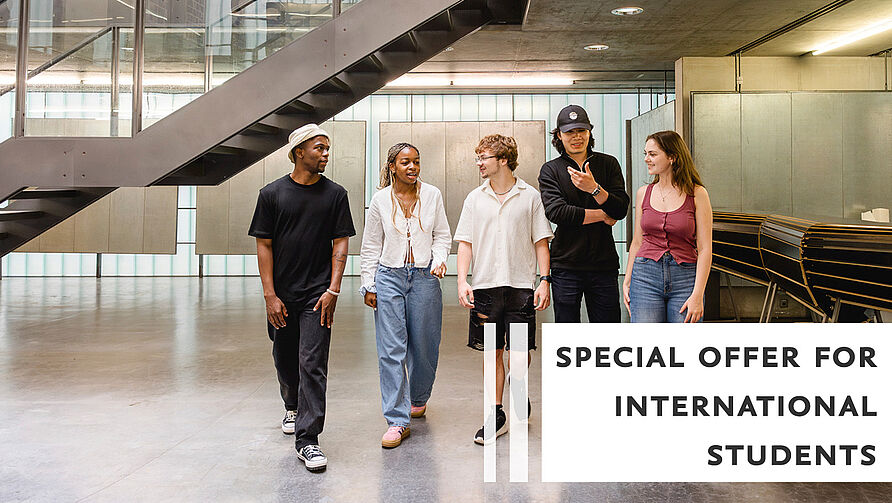 Eine Gruppe von Studierenden geht nebeneinander durch den Architekturpavillon der TU Braunschweig und unterhält sich dabei. 