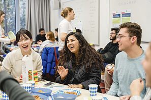 Students sit at tables decorated in Bavarian style and laugh together.