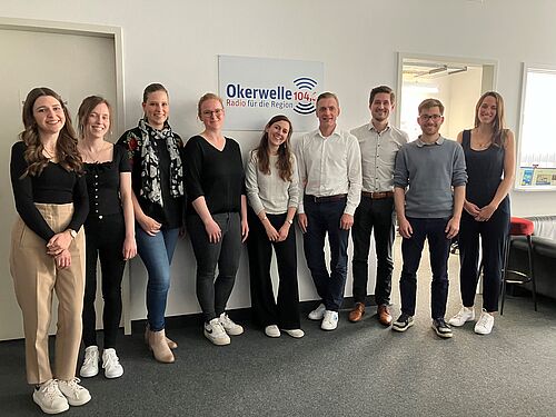 Zu sehen ist eine Gruppe von Personen mit drei Studierenden und drei Alumni*ae der TU Braunschweig sowie Luisa Goldgräbe als Referentin für Stipendien und die Referentinnen für Alumni*ae Management Maike Stelter und Melanie Schaller im Radio Okerwelle Studio.