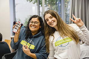 Two International Student Support staff members laugh cheerfully at the camera.