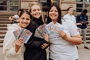 Drei Teilnehmerinnen der Summer School halten Postkarten mit TU Braunschweig-Motiv in die Kamera.