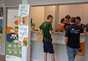 Studierende stehen an einem Tresen und unterhalten sich