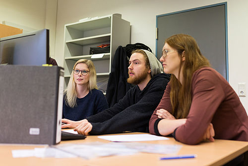 Lehrende bereiten mit einem Studierenden etwas vor