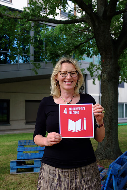 Prof. Dr. Katja Koch hält das SDG 4 in beiden Händen. 