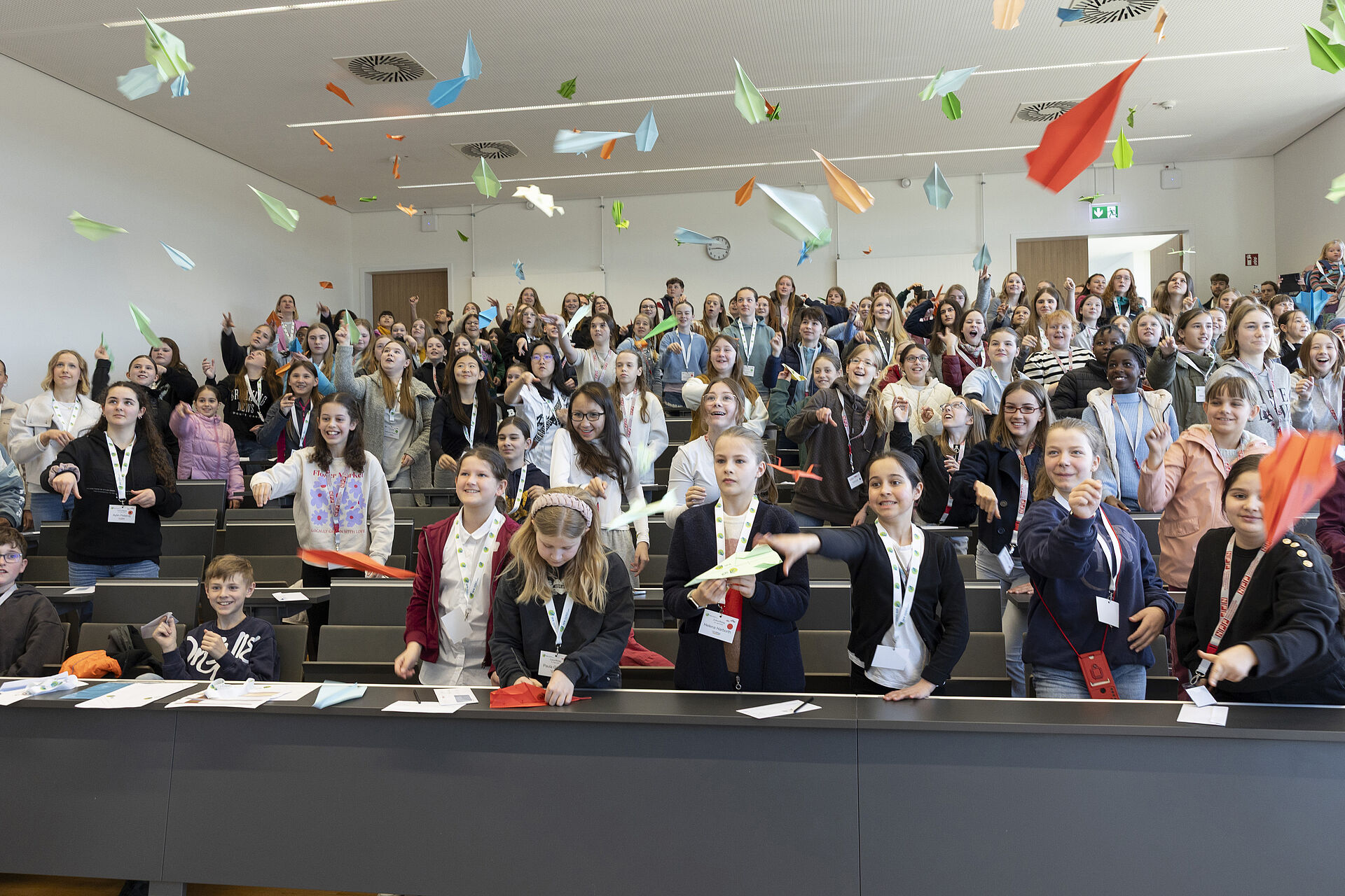Kinder werfen ihre selbstgebastelten Papierflieger im NFF-Hörsaal im Rahmen des Zukunftstages 2025.