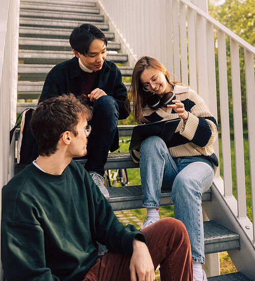 Studierende sitzen auf der Treppe des Studierendenhaus der TU BRaunschweig.