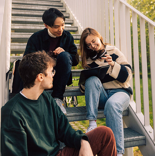 Students sitting on the stairs of the student house 