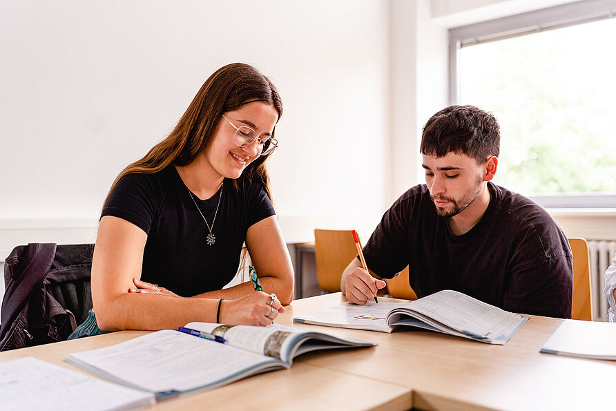Two students sit at a table and study.