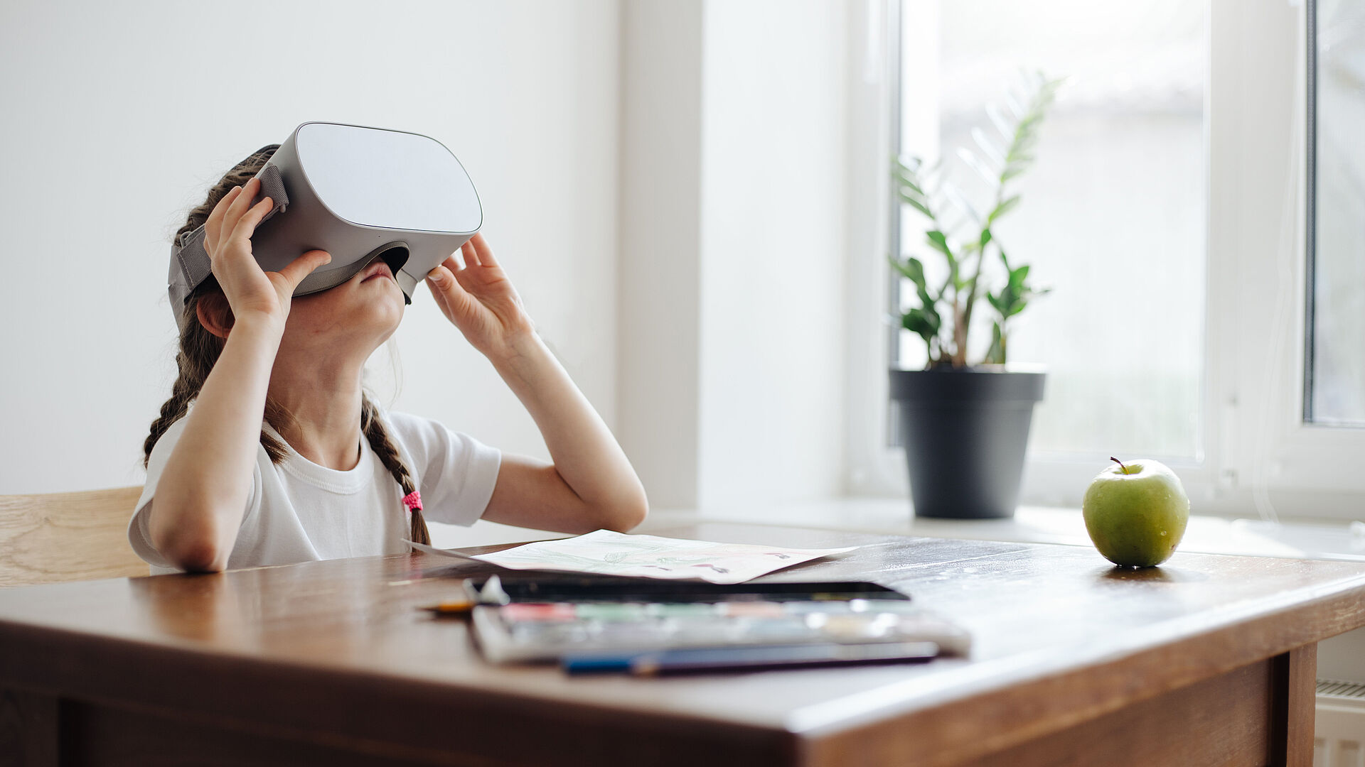 Kid girl using virtual reality glasses at home