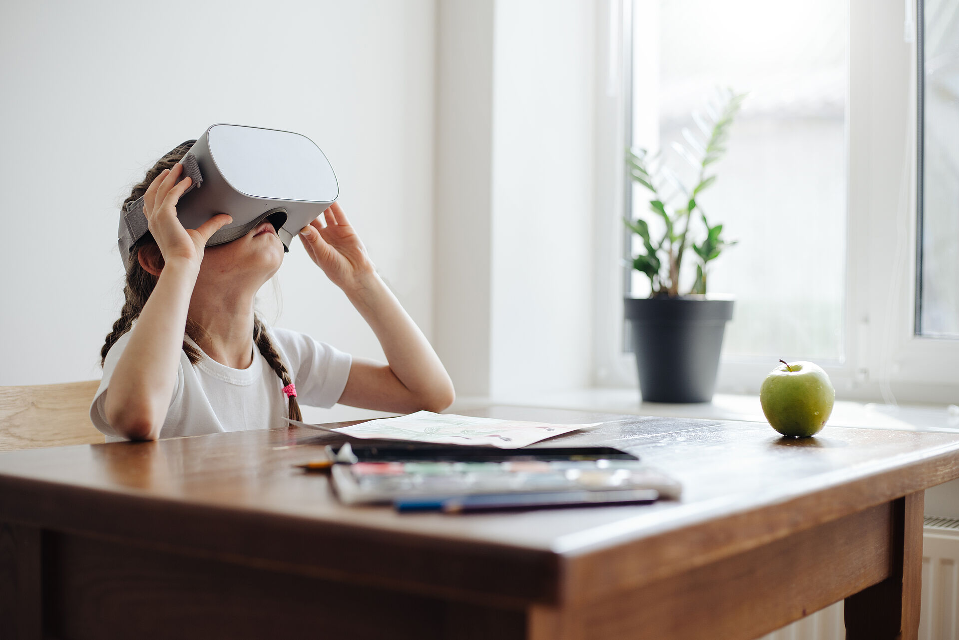 Kid girl using virtual reality glasses at home