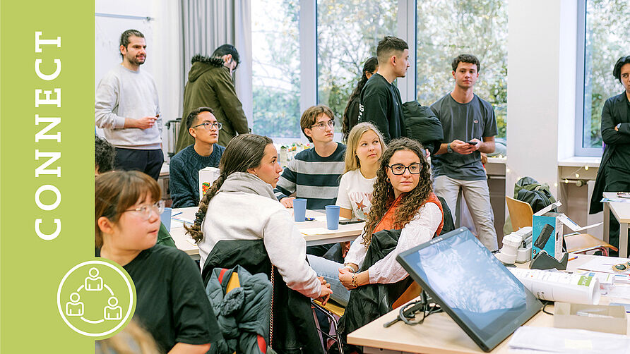 Mehrere Studierende sitzen und stehen in einem Seminarraum im International House.