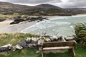 Eine Bank steht an einem Aussichtspunkt mit Blick auf die irische Küste. 